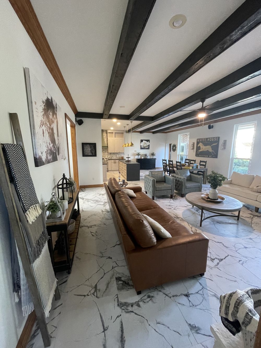 Open living area with exposed wood beams and marble flooring